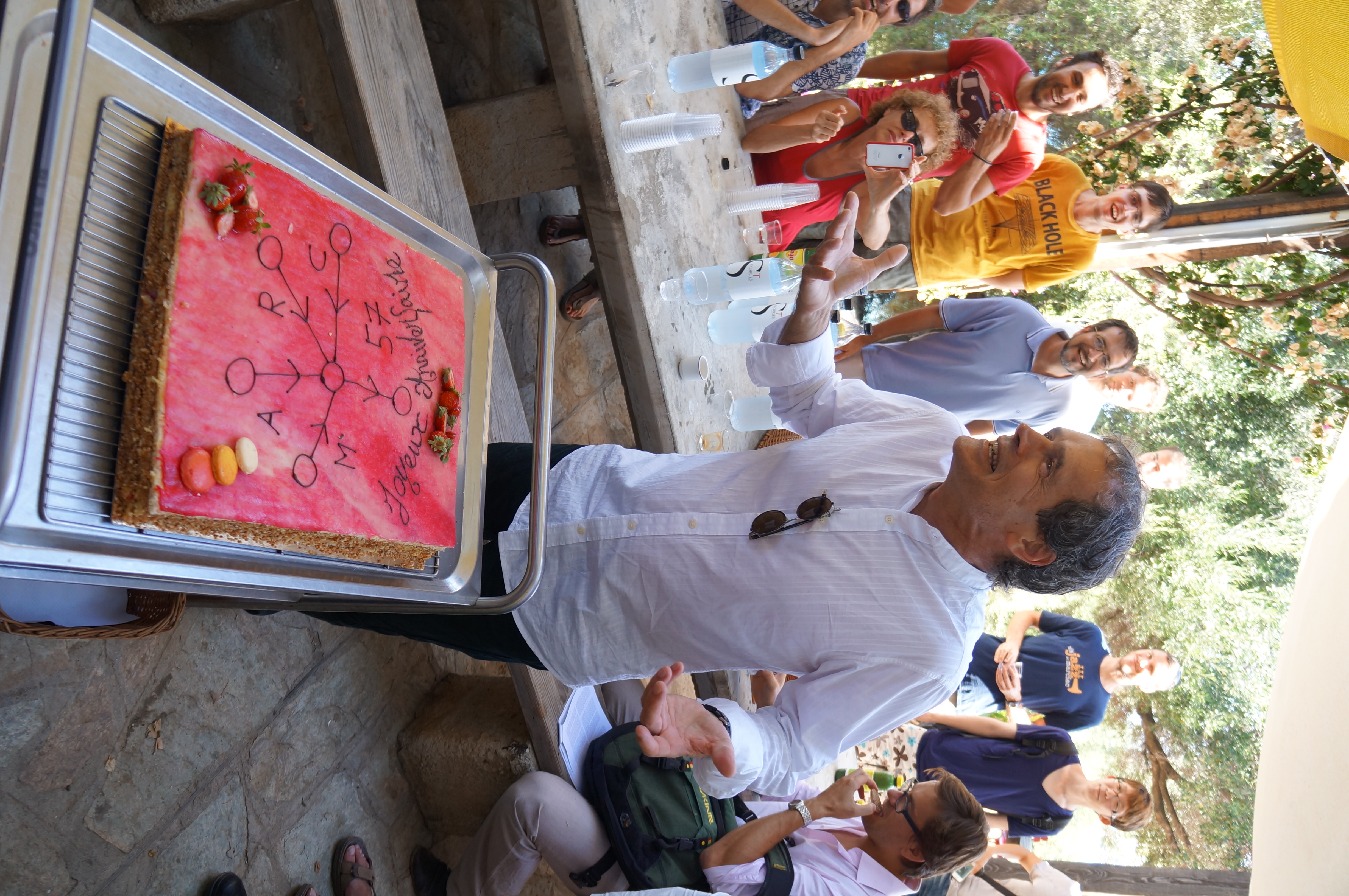 Participants gathering around a celebration cake during the 2014 Cargèse school